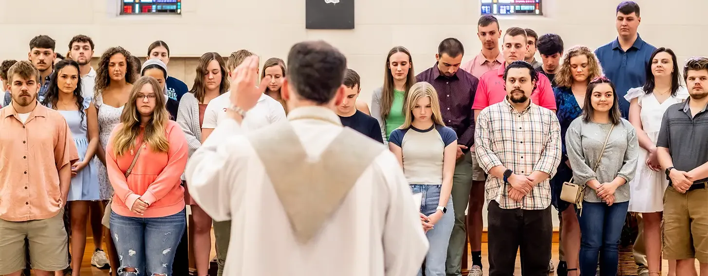 A priest leading a group of students.